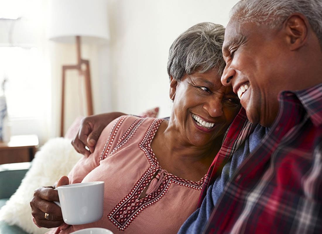 Medicare - Loving Couple Sitting on the Sofa at Home Relaxing with Coffee on the Couch
